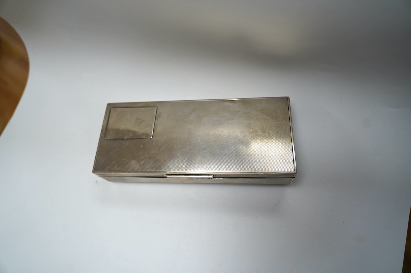 A George V engine turned silver mounted rectangular cigarette box, London, 1935, 21.7cm. Condition - poor